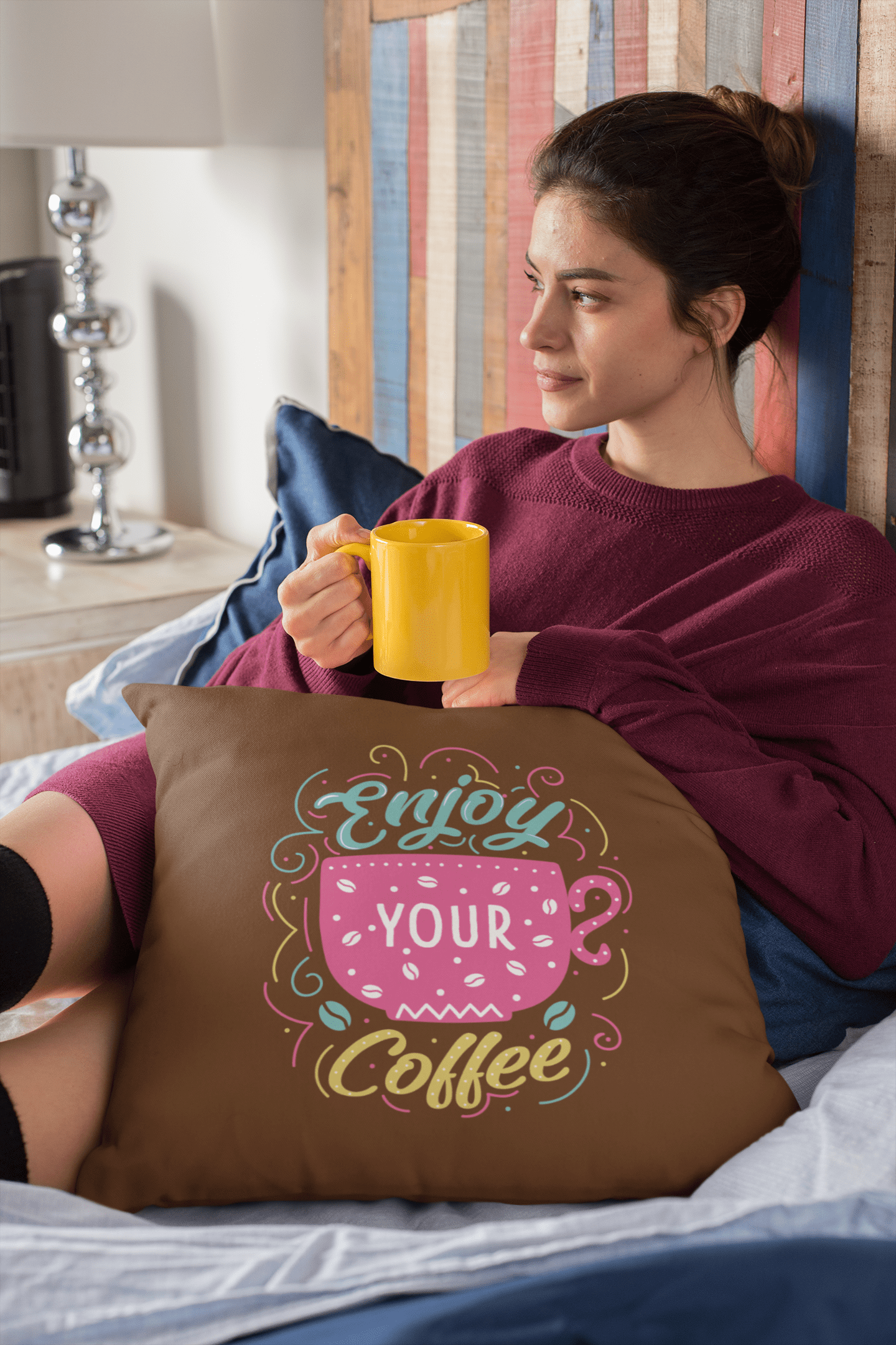 pillow-mockup-of-a-woman-sitting-cozily-on-her-bed-drinking-tea-23572