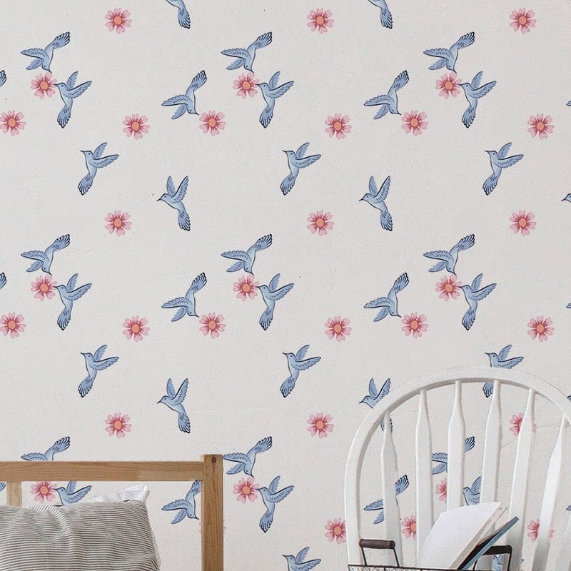 Papel de parede adesivo com padrão floral e pássaros em azul e rosa aplicado em parede de quarto