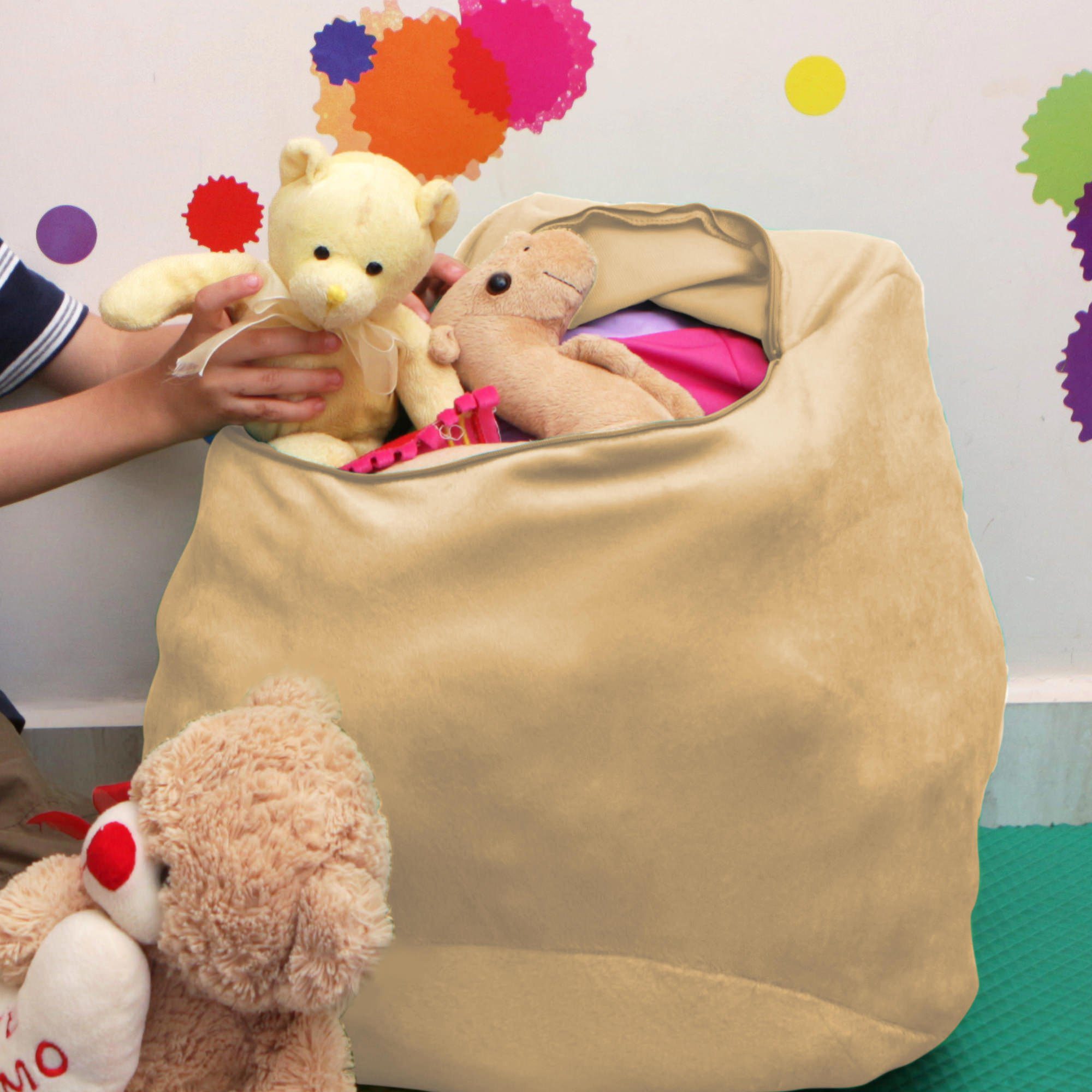 Criança colocando urso de pelúcia dentro do puff organizador infantil revestido em tecido bege claro.