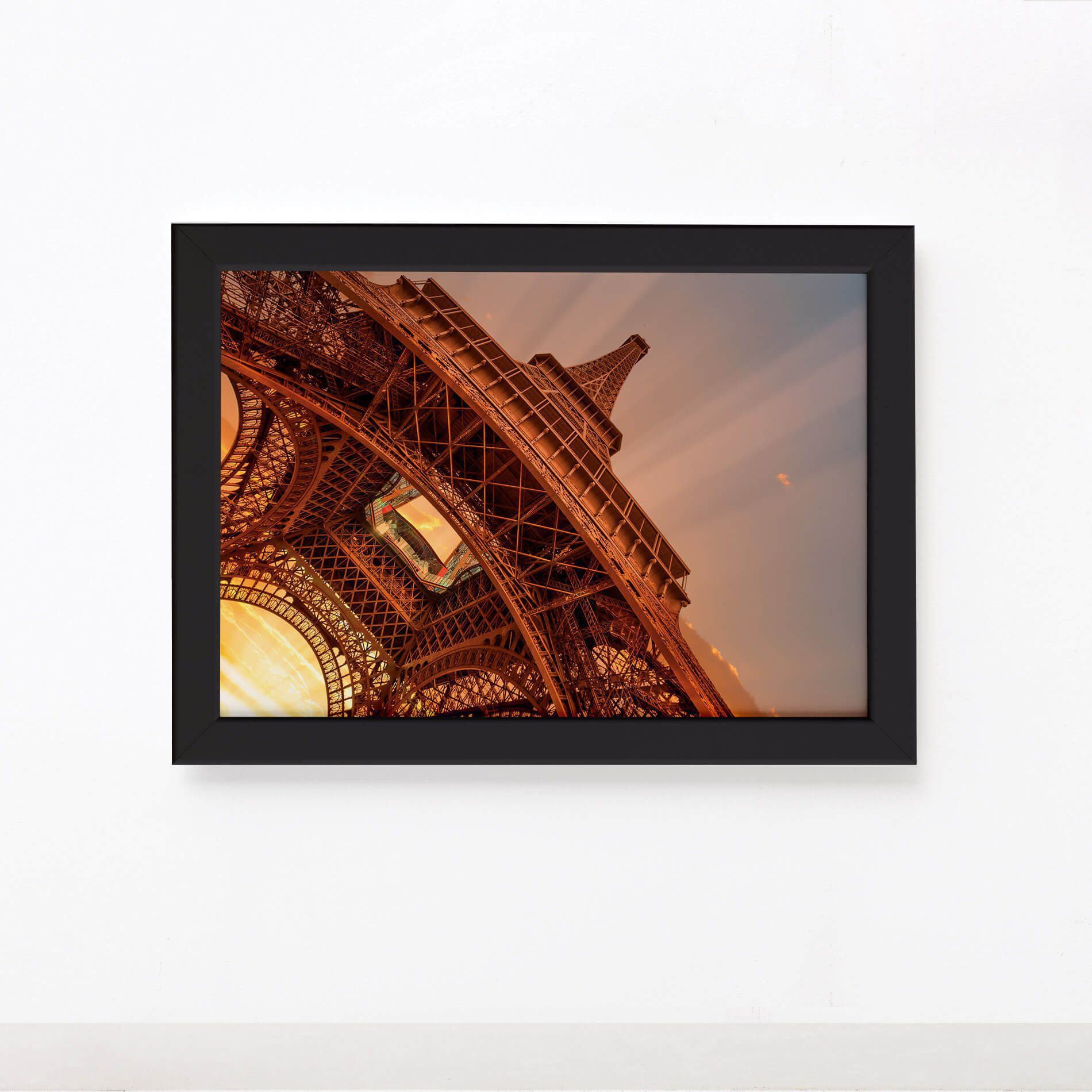 Imagem do quadro decorativo Paris Torre Eiffel com moldura preta, dimensões 22x32cm, pendurado em parede branca.