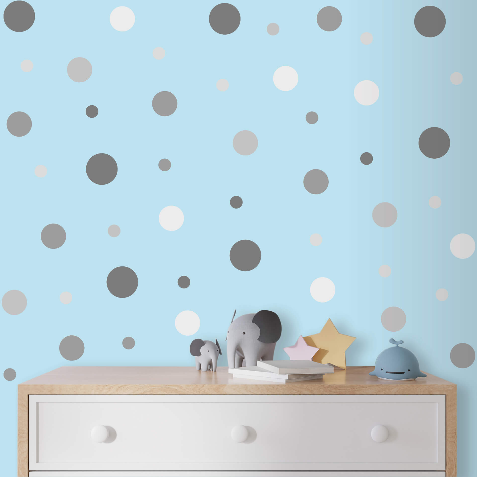 Adesivo de parede para quarto infantil com bolinhas em várias cores, aplicadas sobre parede azul clara. Bolinhas em tons de cinza, branco e bege, distribuídas de forma espaçada e irregular.